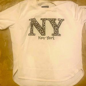 A white sweater with a leopard print sight saying ny